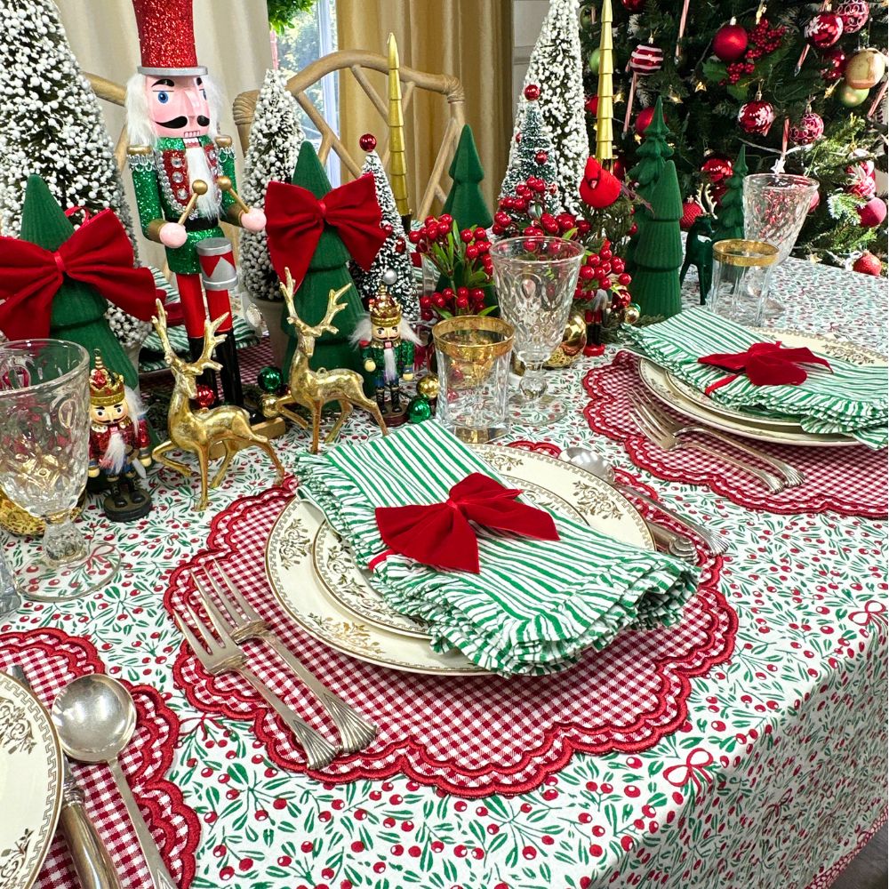 Decorative Christmas table setting with green and red accents, including a nutcracker and Christmas trees, mistletoe print tablecloth, Christmas tablecloth, Christmas luxury placemats and napkins, Christmas napkins